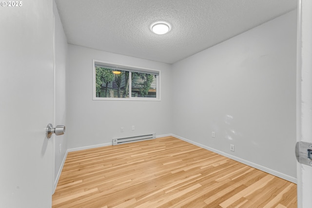 unfurnished room with light wood-type flooring, a textured ceiling, and a baseboard heating unit