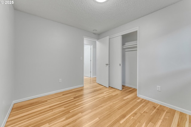 unfurnished bedroom with light hardwood / wood-style floors, a closet, and a textured ceiling