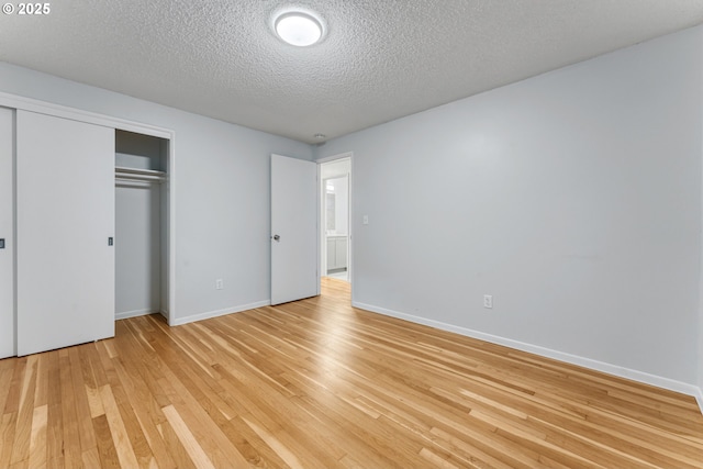 unfurnished bedroom with a textured ceiling, a closet, and light wood-type flooring