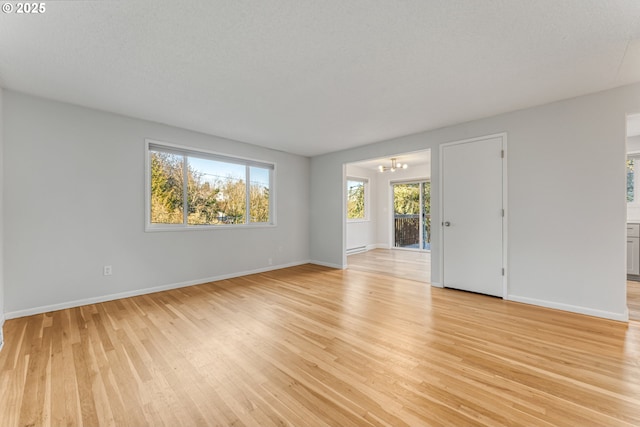 spare room with a chandelier, light hardwood / wood-style floors, and a textured ceiling