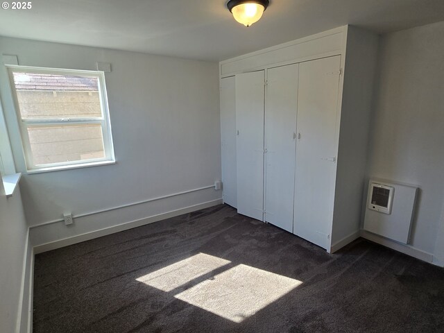 3208 W 7th St, The Dalles, OR 97058 - unfurnished bedroom with a closet, baseboards, heating unit, and dark colored carpet