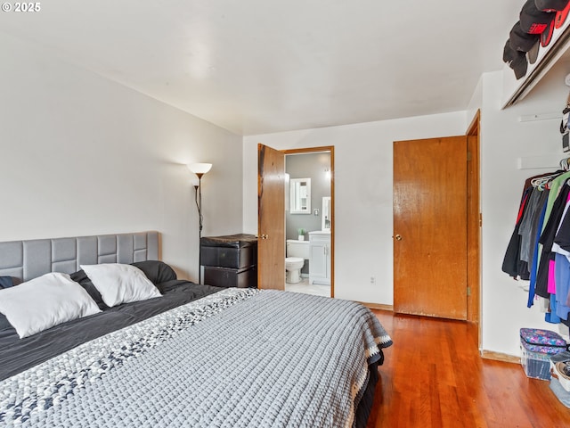 bedroom featuring connected bathroom, baseboards, and wood finished floors