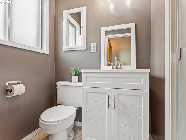bathroom with toilet, baseboards, and vanity