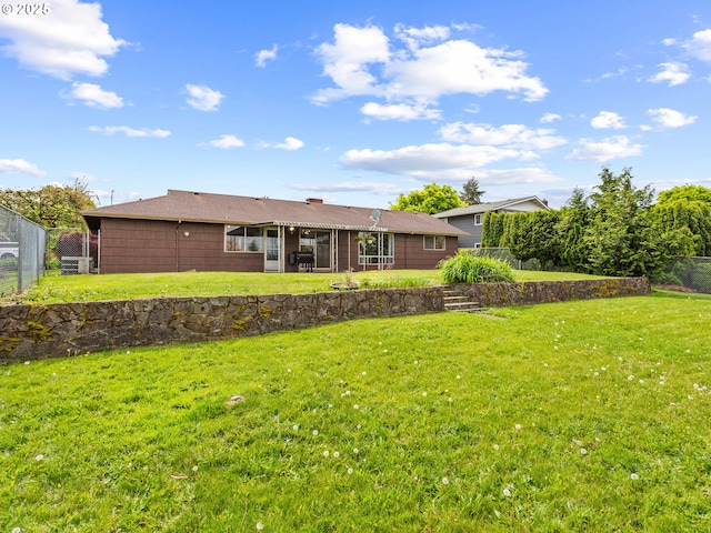 back of property with fence, a sunroom, and a yard