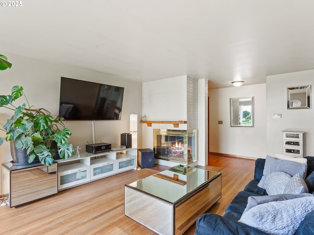 living room with a brick fireplace and wood finished floors