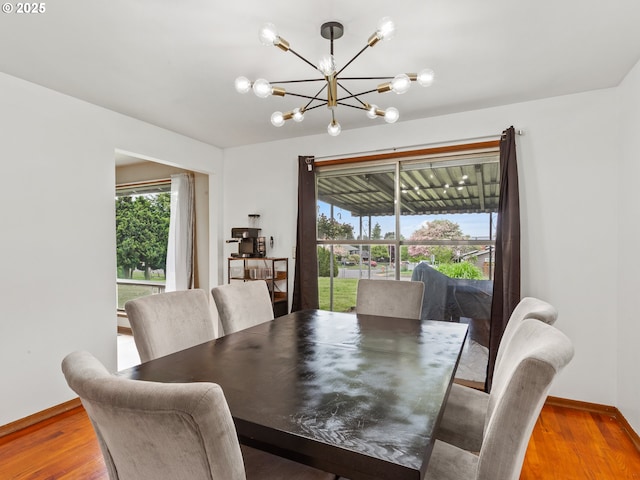 dining space featuring baseboards, plenty of natural light, wood finished floors, and a chandelier