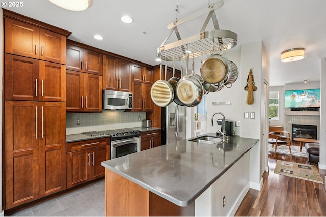 16040 SW Audubon St Unit 101, Beaverton, OR 97003 - kitchen with stainless steel appliances, backsplash, a peninsula, a glass covered fireplace, and recessed lighting