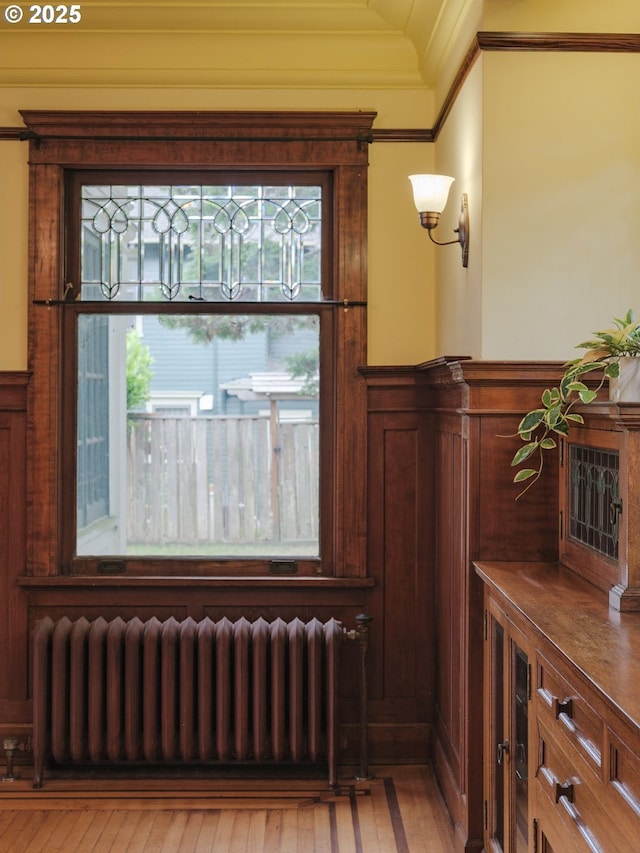 1343 Jerome Ave, Astoria, OR 97103 - detailed view of radiator heating unit, ornamental molding, a wainscoted wall, and wood finished floors