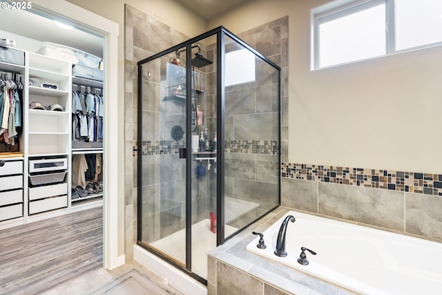 bathroom with a bath, a shower stall, and a walk in closet