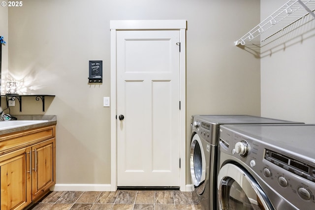 washroom featuring washer and dryer, baseboards, cabinet space, and a sink