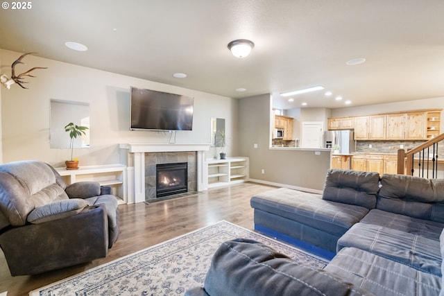 living room with recessed lighting, baseboards, a tile fireplace, and light wood finished floors