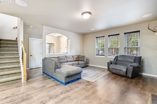 living room with stairs, wood finished floors, and baseboards