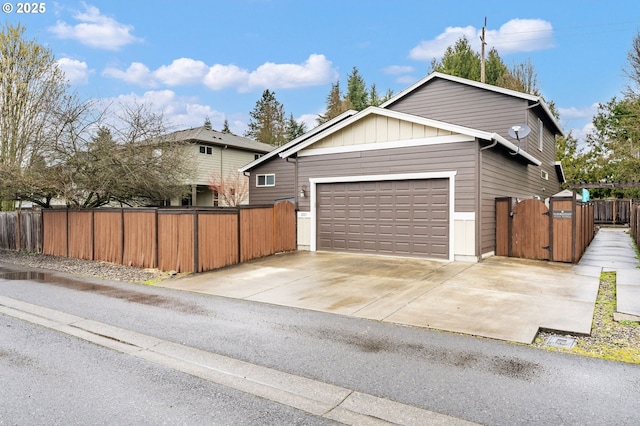 view of front of home with a gate, fence, an attached garage, concrete driveway, and board and batten siding