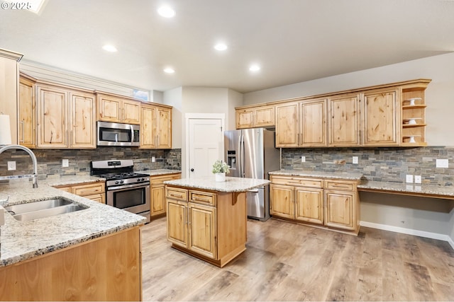 kitchen featuring light stone counters, open shelves, a sink, stainless steel appliances, and light wood-style floors