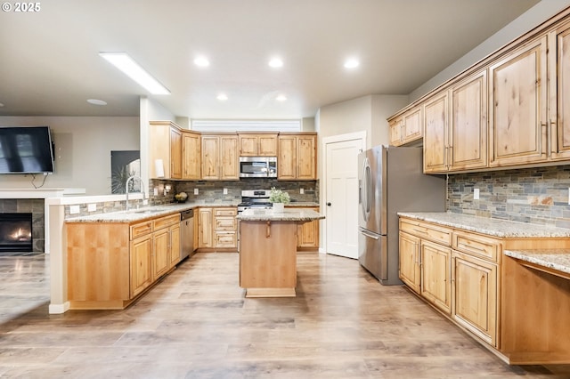 kitchen featuring a sink, light stone counters, a kitchen island, and stainless steel appliances