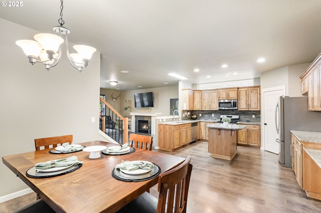 dining room featuring a chandelier, stairway, a tiled fireplace, light wood-style flooring, and recessed lighting