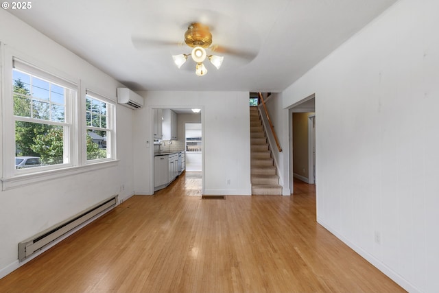 2000 Harney St, Vancouver, WA 98660 - unfurnished living room featuring a baseboard radiator, a wall mounted air conditioner, ceiling fan, stairs, and light wood finished floors