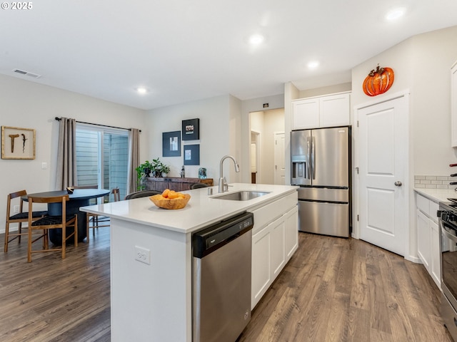 kitchen featuring sink, a center island with sink, dark hardwood / wood-style flooring, stainless steel appliances, and white cabinets