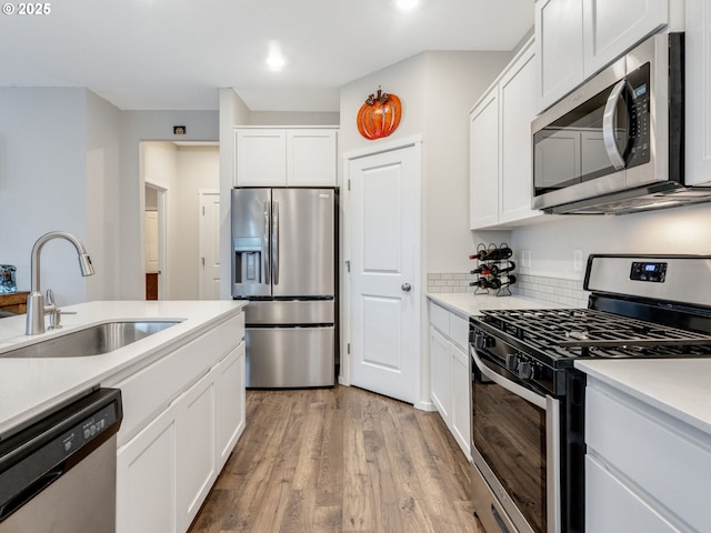 kitchen with white cabinetry, sink, light wood-type flooring, and appliances with stainless steel finishes