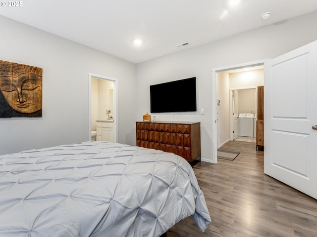 bedroom featuring ensuite bath, washer / clothes dryer, and hardwood / wood-style floors