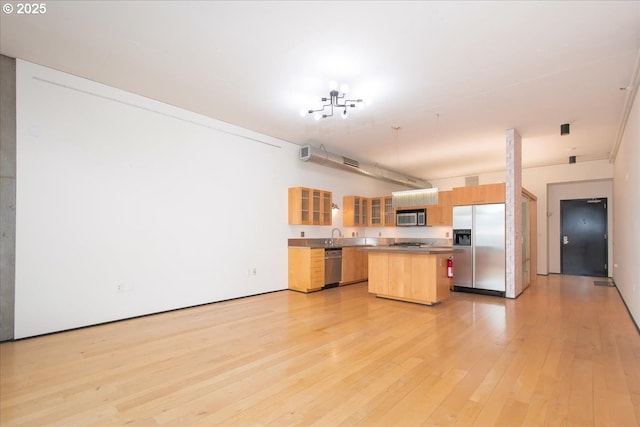 kitchen with appliances with stainless steel finishes, a center island, and light hardwood / wood-style floors