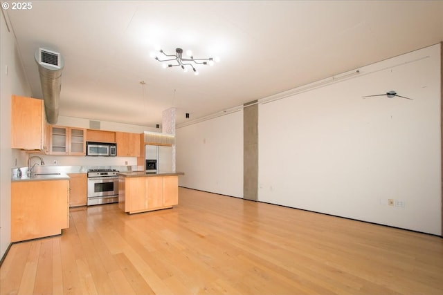 kitchen featuring sink, light brown cabinets, light wood-type flooring, appliances with stainless steel finishes, and a kitchen island