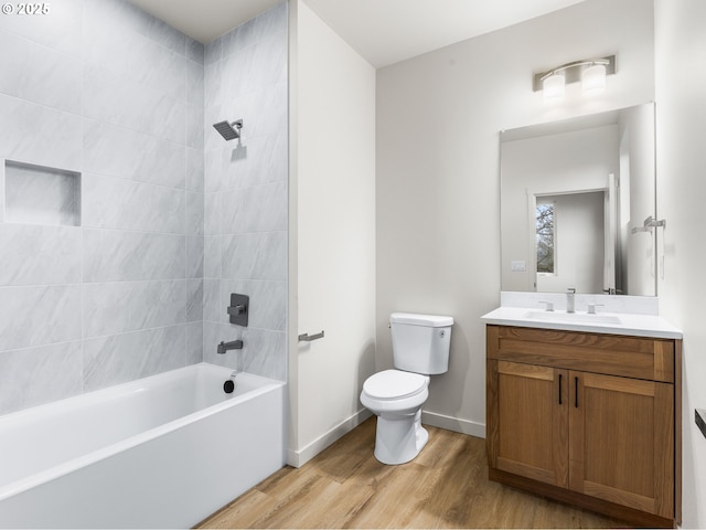 bathroom with vanity, washtub / shower combination, wood finished floors, baseboards, and toilet