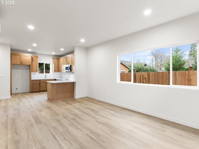 kitchen with stainless steel microwave, open floor plan, light wood-type flooring, recessed lighting, and white electric range oven