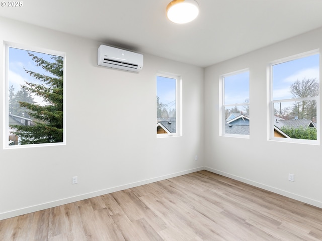 empty room with an AC wall unit, baseboards, and a wealth of natural light