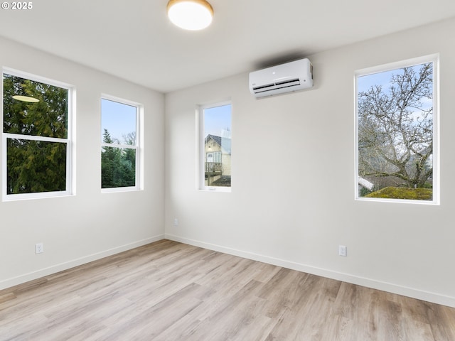 unfurnished room featuring wood finished floors, baseboards, and a wall mounted air conditioner