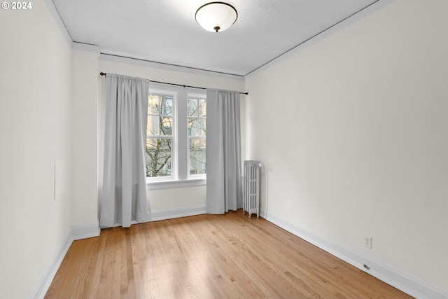 spare room with radiator heating unit and light hardwood / wood-style floors