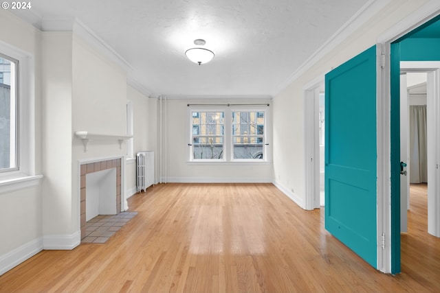 unfurnished living room featuring a tile fireplace, radiator heating unit, ornamental molding, and light hardwood / wood-style flooring