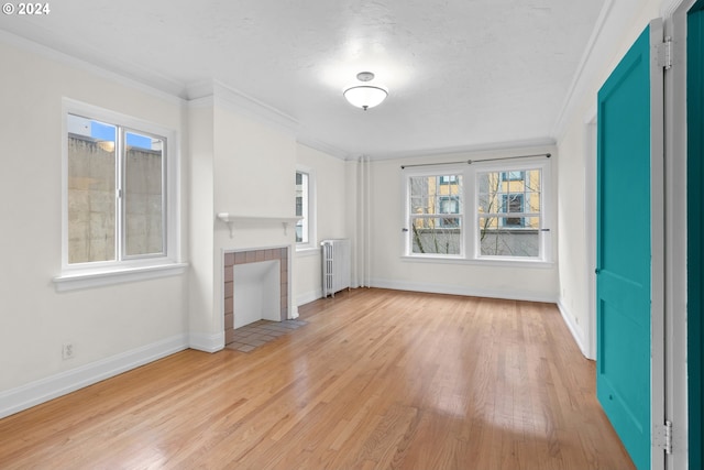 unfurnished living room featuring a textured ceiling, radiator heating unit, light hardwood / wood-style floors, a tile fireplace, and crown molding