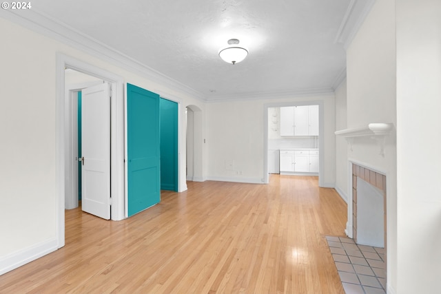 unfurnished living room featuring a tile fireplace, light hardwood / wood-style flooring, and ornamental molding