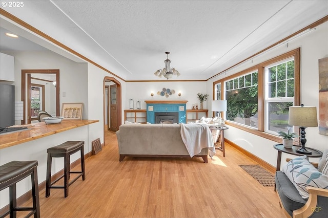 3700 NE Maywood Pl, Portland, OR 97220 - living area with light wood finished floors, baseboards, a chandelier, arched walkways, and a fireplace