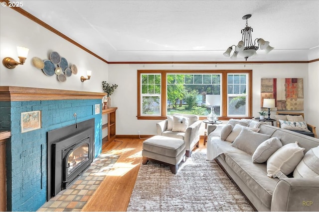 3700 NE Maywood Pl, Portland, OR 97220 - living room featuring light wood-style floors, ornamental molding, a chandelier, baseboards, and a tiled fireplace