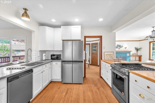 3700 NE Maywood Pl, Portland, OR 97220 - kitchen with stainless steel appliances, a sink, light wood-type flooring, white cabinets, and recessed lighting