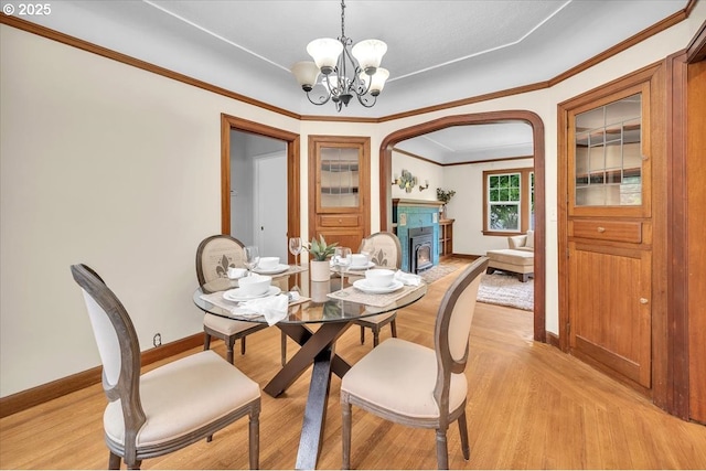 3700 NE Maywood Pl, Portland, OR 97220 - dining area featuring baseboards, a chandelier, a warm lit fireplace, light wood-style flooring, and ornamental molding