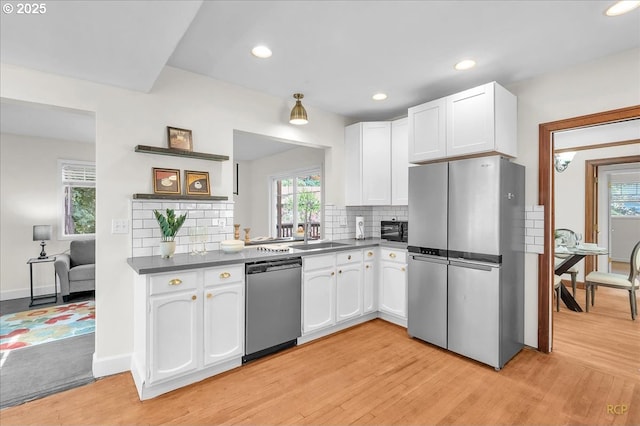 3700 NE Maywood Pl, Portland, OR 97220 - kitchen featuring stainless steel appliances, white cabinetry, light wood finished floors, dark countertops, and tasteful backsplash