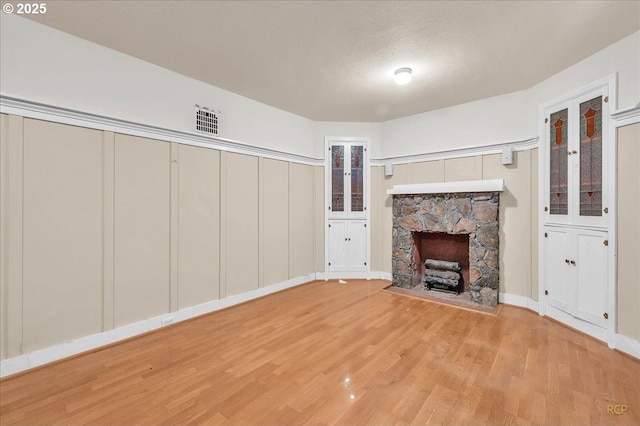 3700 NE Maywood Pl, Portland, OR 97220 - unfurnished living room featuring wood finished floors, a fireplace, a textured ceiling, and baseboards