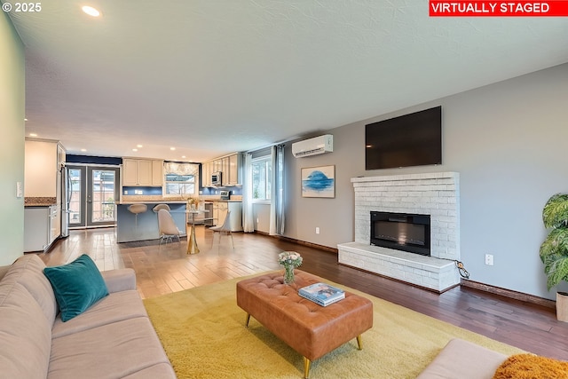 living room with a brick fireplace, light wood-type flooring, and a wall mounted AC