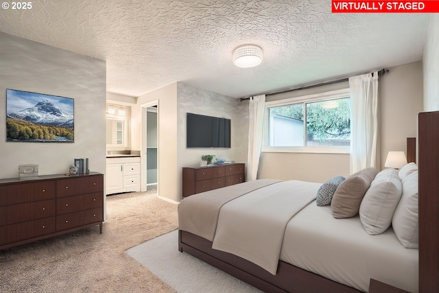 carpeted bedroom featuring ensuite bathroom and a textured ceiling