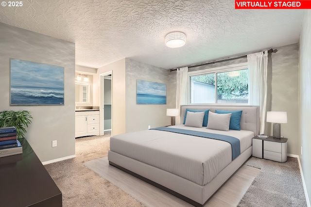 carpeted bedroom with a textured ceiling and connected bathroom