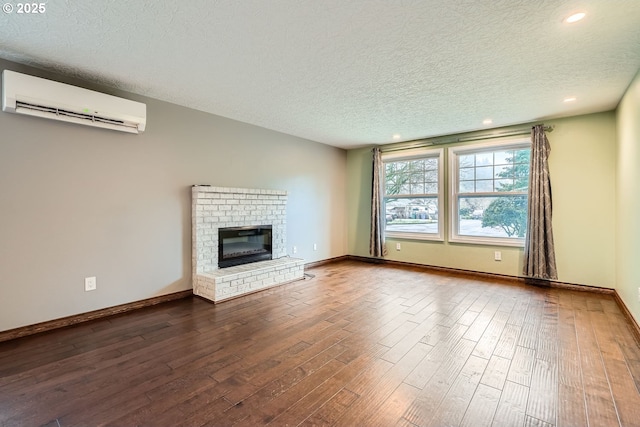 unfurnished living room with a fireplace, a textured ceiling, a wall mounted air conditioner, and hardwood / wood-style flooring