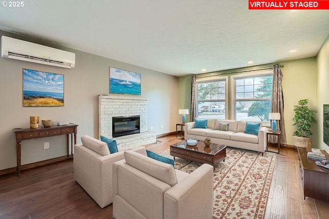 living room with a wall mounted air conditioner, a fireplace, and wood-type flooring