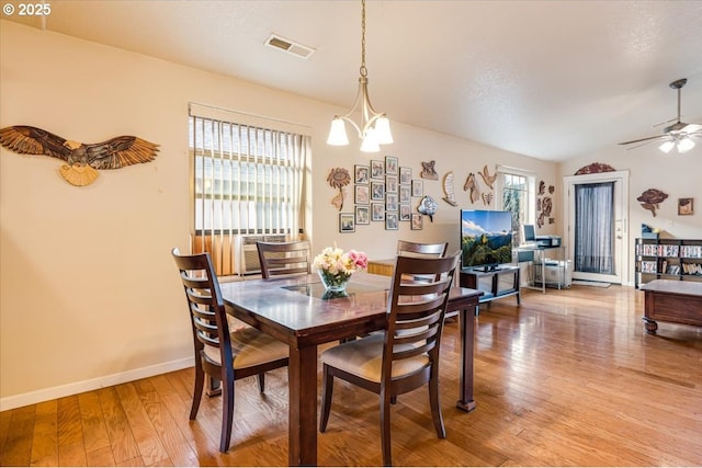 dining area with baseboards, visible vents, wood finished floors, and ceiling fan with notable chandelier