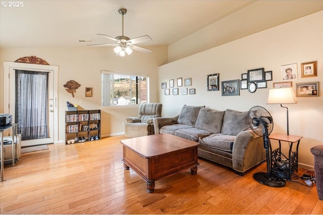 living room featuring visible vents, light wood-style floors, vaulted ceiling, ceiling fan, and baseboards