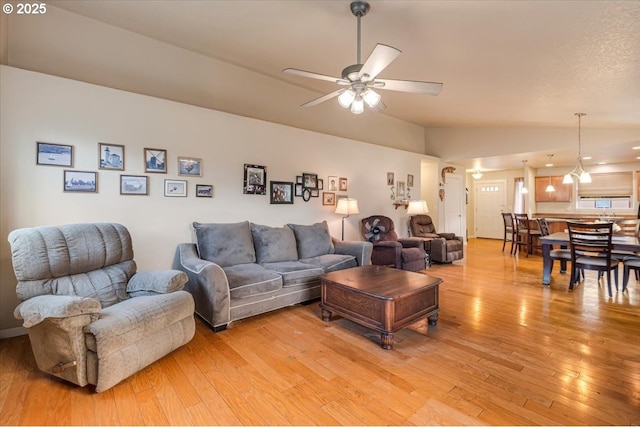 living area with lofted ceiling, ceiling fan, and light wood-type flooring