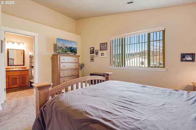 bedroom with connected bathroom, light colored carpet, visible vents, and a sink