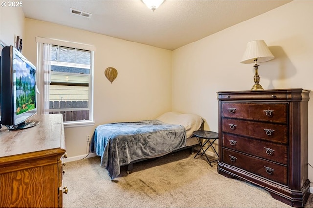 bedroom with visible vents, light carpet, and baseboards